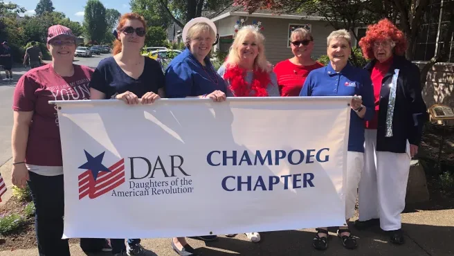 Members of the Daughters of the American Revolution holding a banner with the logo of the organization