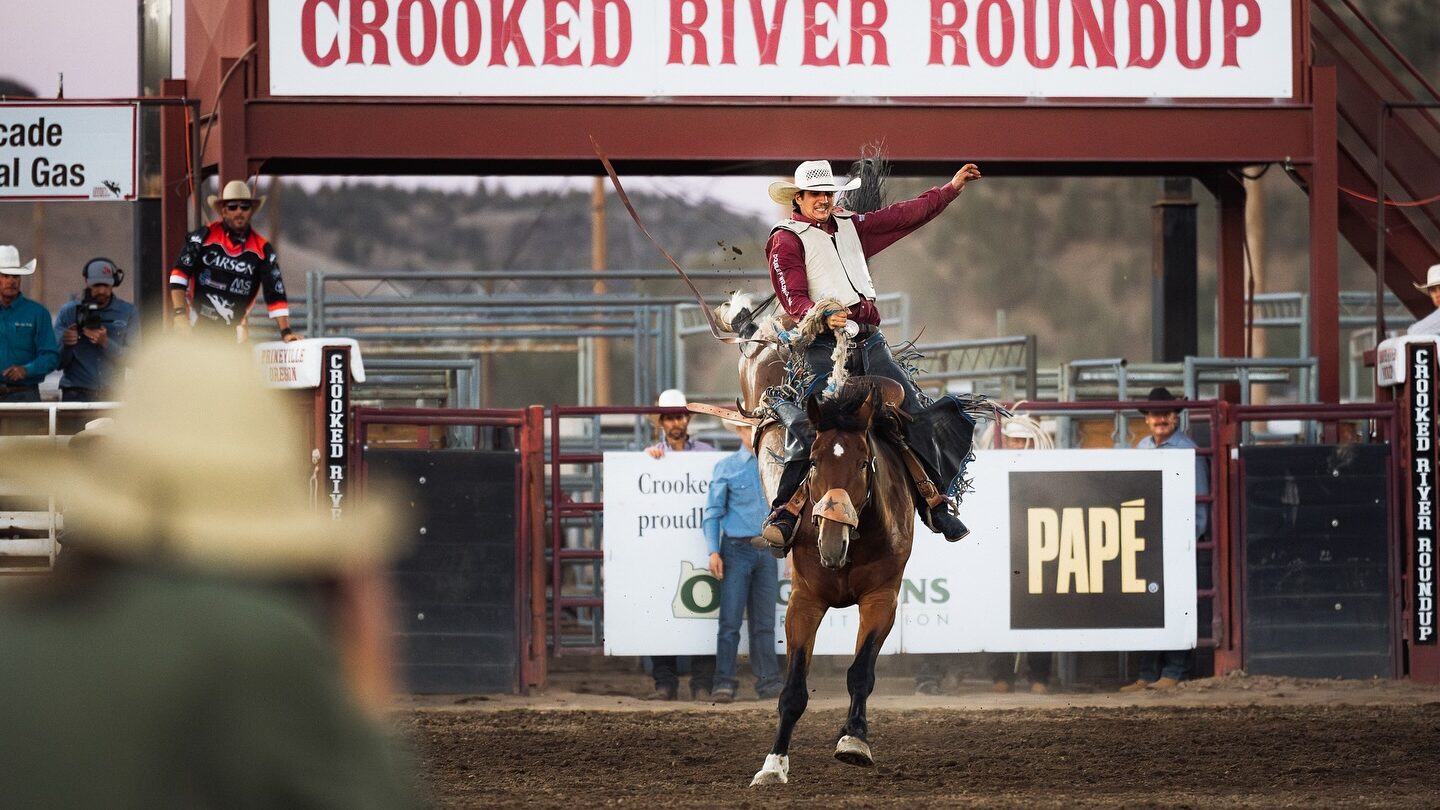 Photo of a cowboy riding a bucking horse at the Crooked River Roundup